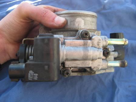 Bottom of throttle body showing IACV (Intake Air Control Valve). Right side is where coolant lines enter (facing the rear of the vehicle) and left side is the electronic part of the IACV.