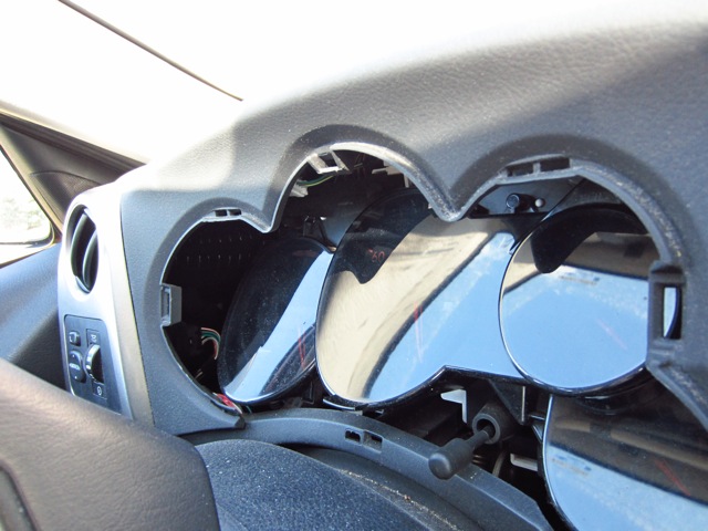 Outer trim bezel removed, showing attachment points. Inner dark-tinted plastic is still in place, and still VERY reflective.